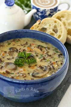 a blue bowl filled with mushroom soup next to some slices of bread on a table