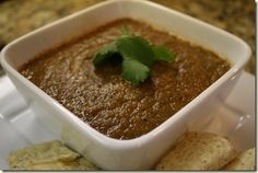 a white bowl filled with soup next to crackers and cilantro on a plate