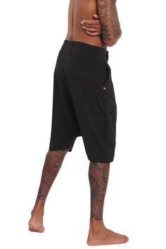 Breathable, super lightweight, water resistant active fabric meets tailored structure in these black techwear shorts. The Dublin Mens Drop Crotch Shorts have a streetwear aesthetic but function as a multi purpose garment. Comfortable enough to lounge in and suitable to swim in; the perfect shorts for travelers and spontaneous souls. FEATURES: Harem style: low dropped crotch Long length, hits just below the knee Four pockets, two with zippers, one of which is hidden Belt loops Diagonal zip fly Ma Cotton Drop Crotch Bottoms For Streetwear, Techwear Shorts, Techwear Cotton Shorts With Built-in Liner, Black Techwear, 4-way Stretch Activewear Shorts With Functional Drawstring, Drop Crotch Shorts, Streetwear Cotton Moisture-wicking Shorts, Streetwear Shop, Streetwear Aesthetic