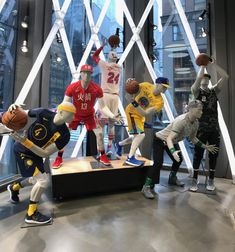 a group of mannequins are posed in front of a window with basketball uniforms