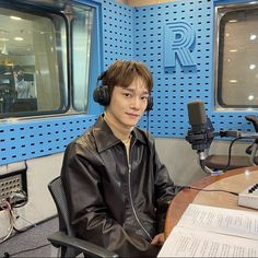 a man sitting at a table with headphones on in front of a radio microphone