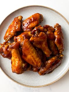 a white plate topped with chicken wings covered in sauce