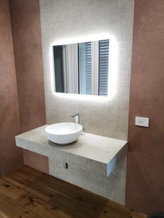 a white sink sitting under a bathroom mirror next to a wall mounted faucet