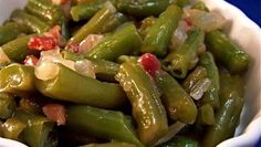 a white bowl filled with green beans on top of a blue tablecloth covered table