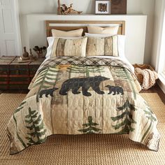 a bed with a bear and pine tree quilt on the comforter in a bedroom