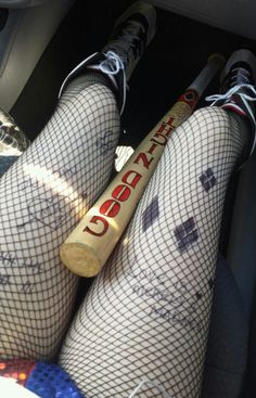 the legs and ankles of a woman in fishnet stockings, holding a baseball bat