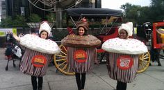 three people in costumes holding up giant cupcakes