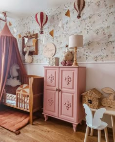 a child's room with pink furniture and hot air balloons hanging from the wall