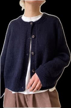 a woman wearing a blue cardigan sweater and tan pants with her hands in her pockets