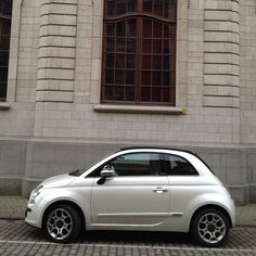 a small white car parked in front of a building