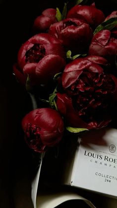 a bouquet of red flowers sitting on top of a white plate next to a box