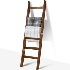 a wooden ladder with blankets on it against a white wall