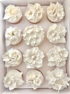 cupcakes decorated with white flowers in a box