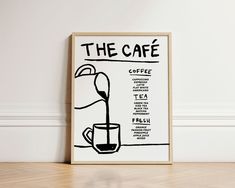 a coffee poster on the wall next to a wooden table with a cup and saucer