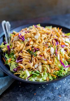 a salad with chicken, carrots, and lettuce in a black bowl