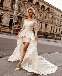 a woman is walking down the street in a white dress with long sleeves and high heels