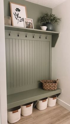 a green bench with three baskets on it and some pictures hanging above the bench in front of it