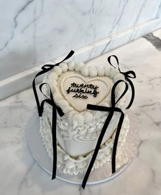 a heart - shaped cake with black ribbon on a marble countertop in the shape of a box