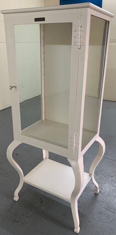 a white cabinet sitting on top of a cement floor