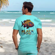 a man standing on the beach wearing a t - shirt that says black fish