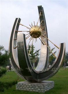 a large metal clock sitting in the middle of a field