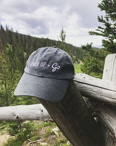 a hat that is sitting on top of a wooden fence near some trees and grass