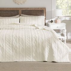 a bed with white bedspread and pillows in a room