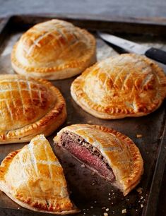 several pastries on a baking sheet with a knife and fork next to them, ready to be eaten