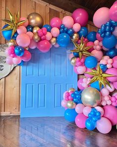 a bunch of balloons that are on the ground in front of a blue door and wooden floor