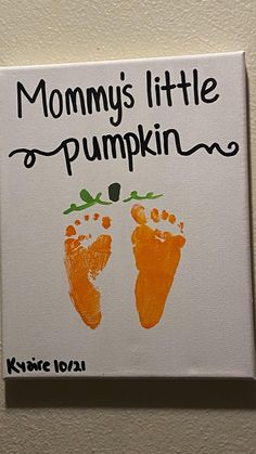 there is a sign that says mommy's little pumpkin and two feet painted on it