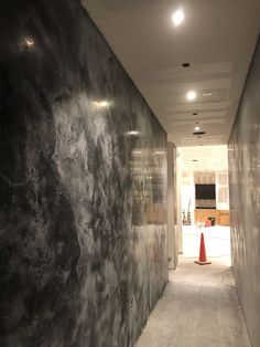 an empty hallway with black marble walls and orange cones on the floor in front of it