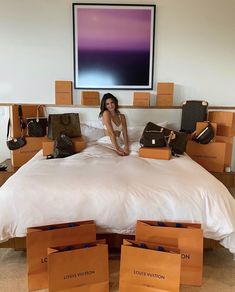 a woman sitting on top of a bed surrounded by boxes