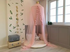 a pink canopy bed in a child's room with flowers on the wall and floor