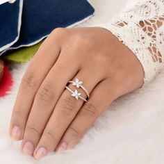 a woman's hand wearing a ring with three flowers on the middle of it