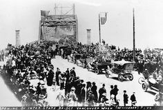 an old black and white photo of people in front of a bridge with cars on it