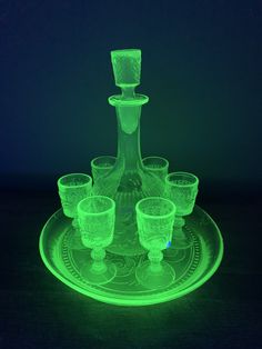 a green glass set on top of a plate in the middle of a dark room