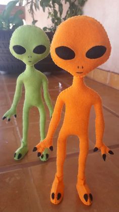 two alien dolls sitting on top of a tiled floor