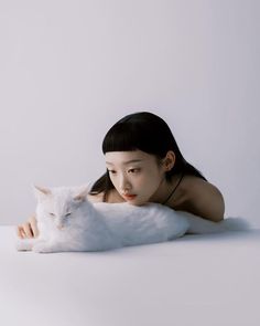 a woman laying on the ground with a white cat