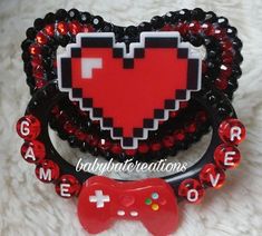 two pieces of red and black beaded heart hair clips with video game controllers attached to them