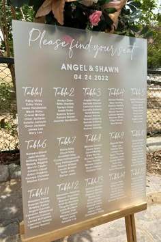 the seating chart for an event is displayed on a wooden easel with flowers in it