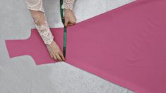 a woman measuring the length of a pink piece of fabric