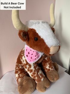 a brown and white stuffed cow sitting on top of a table next to a pink wall