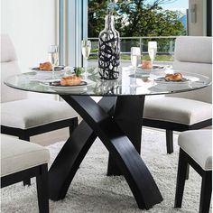 a glass table with chairs around it and a vase on the table next to it