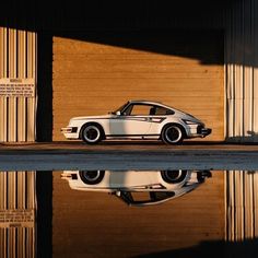 a white sports car parked in front of a garage door next to a reflecting pool