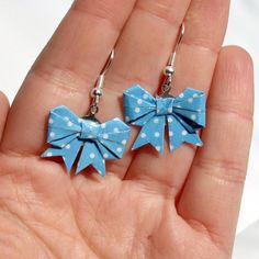 pair of blue and white polka dot bows dangling from silver earwires in hand