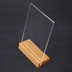 a clear acrylic display stand with a wooden base on a black table top