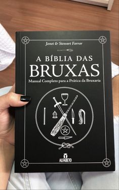 a person holding up a book about bruxas in front of their face and hands