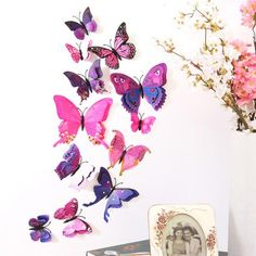 there are many pink and purple butterflies on the wall next to a vase with flowers