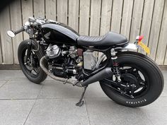 a black motorcycle parked next to a wooden wall