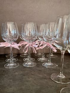 six wine glasses with pink bows on them are lined up in a row and ready to be filled